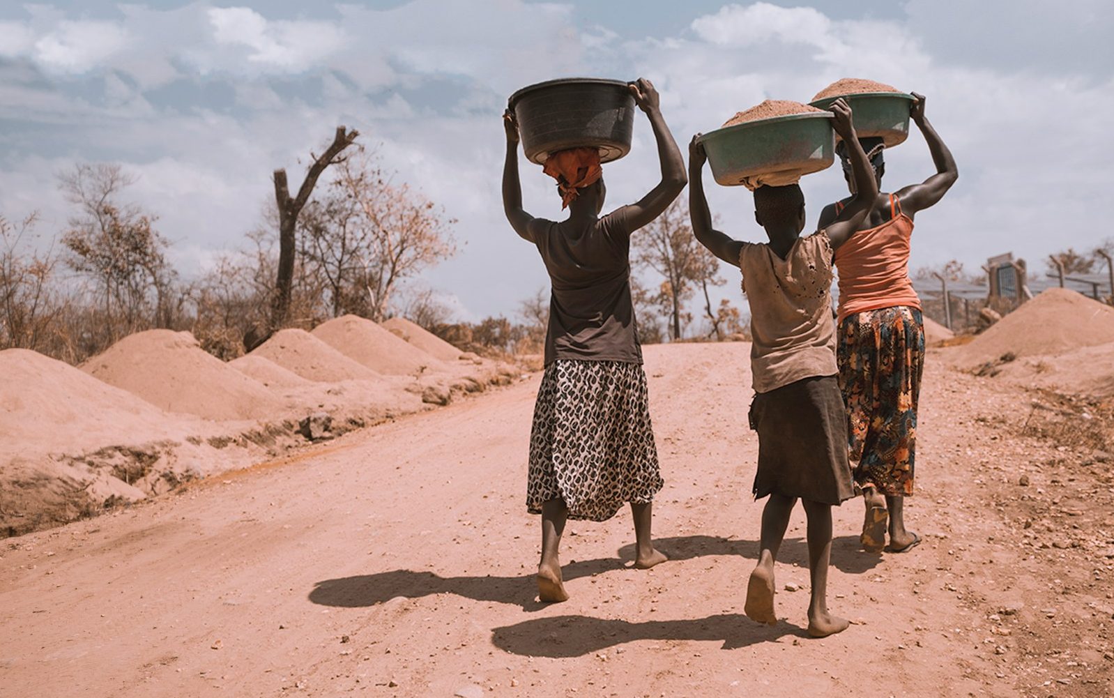 three women carrying basin while walking barefoot