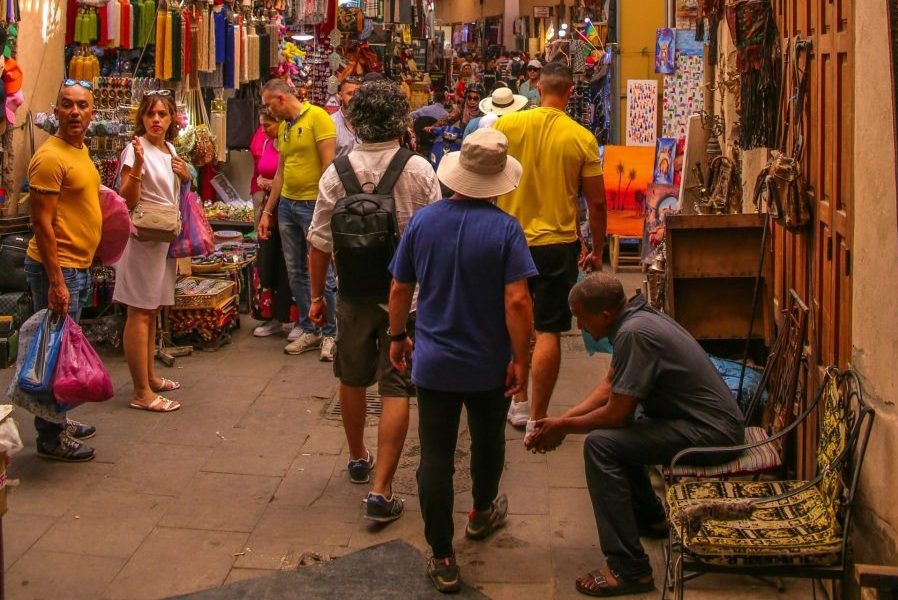 Busy street scene in Marrakech medina featuring colorful shops and local visitors. Experience Moroccan culture.